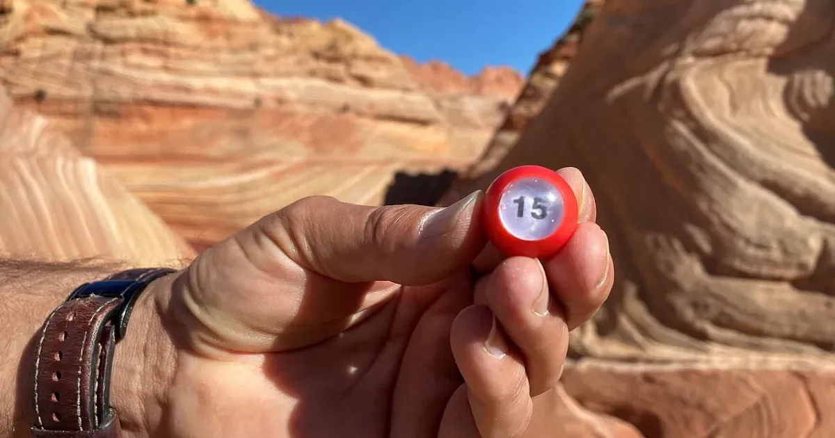 Hand holding red bingo ball number 15 close up