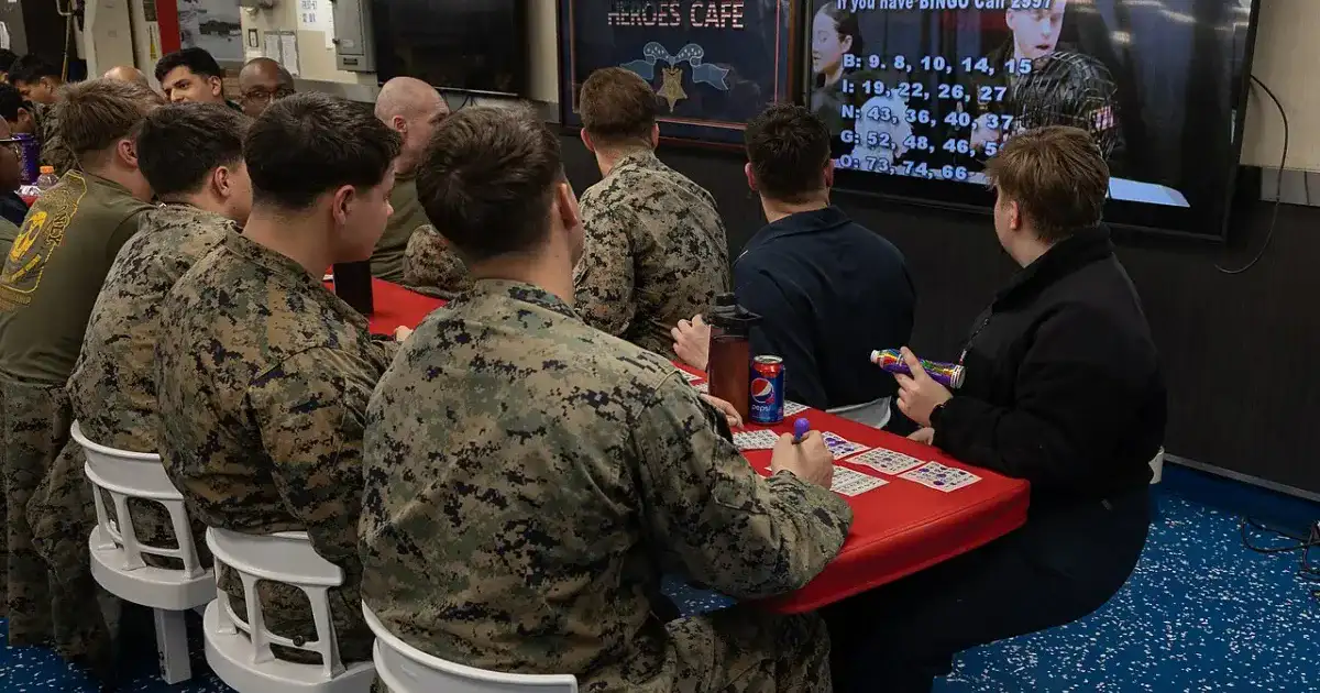 Bingo caller standing next to a large bingo number board