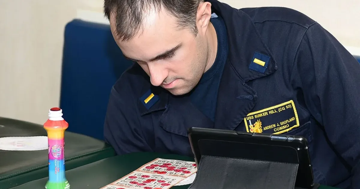 Navy sailor playing bingo with dauber and cards on table